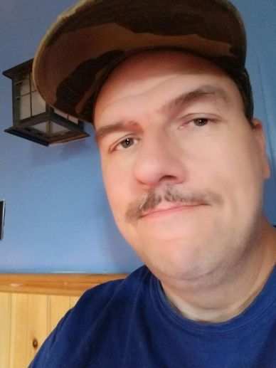 Man wearing a camouflage hat and blue shirt.