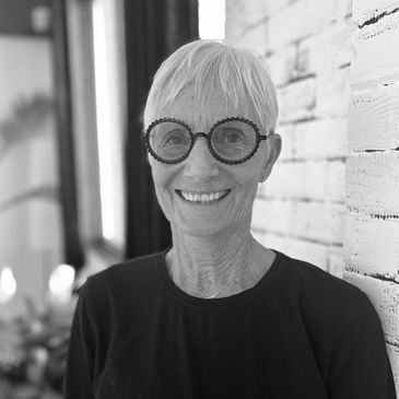 Smiling elderly woman with short white hair and round glasses.