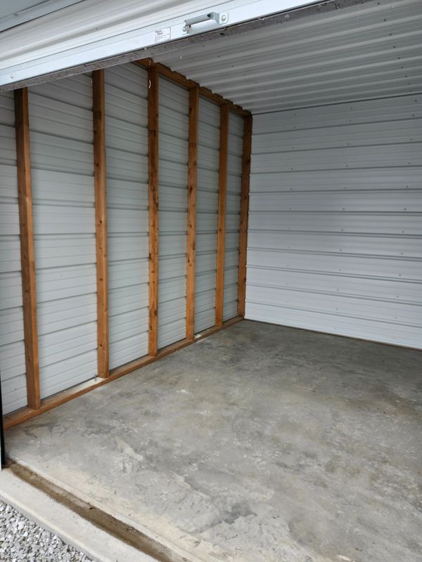 Empty metal garage with wooden framing and concrete floor.