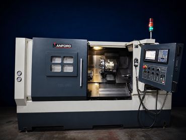 Máquina CNC industrial encendida en ambiente oscuro.