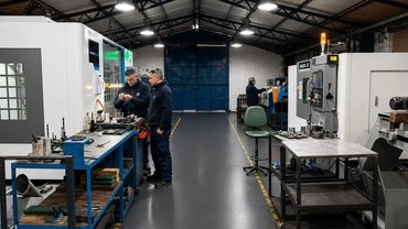 Dos técnicos trabajando en máquinas industriales en un taller.