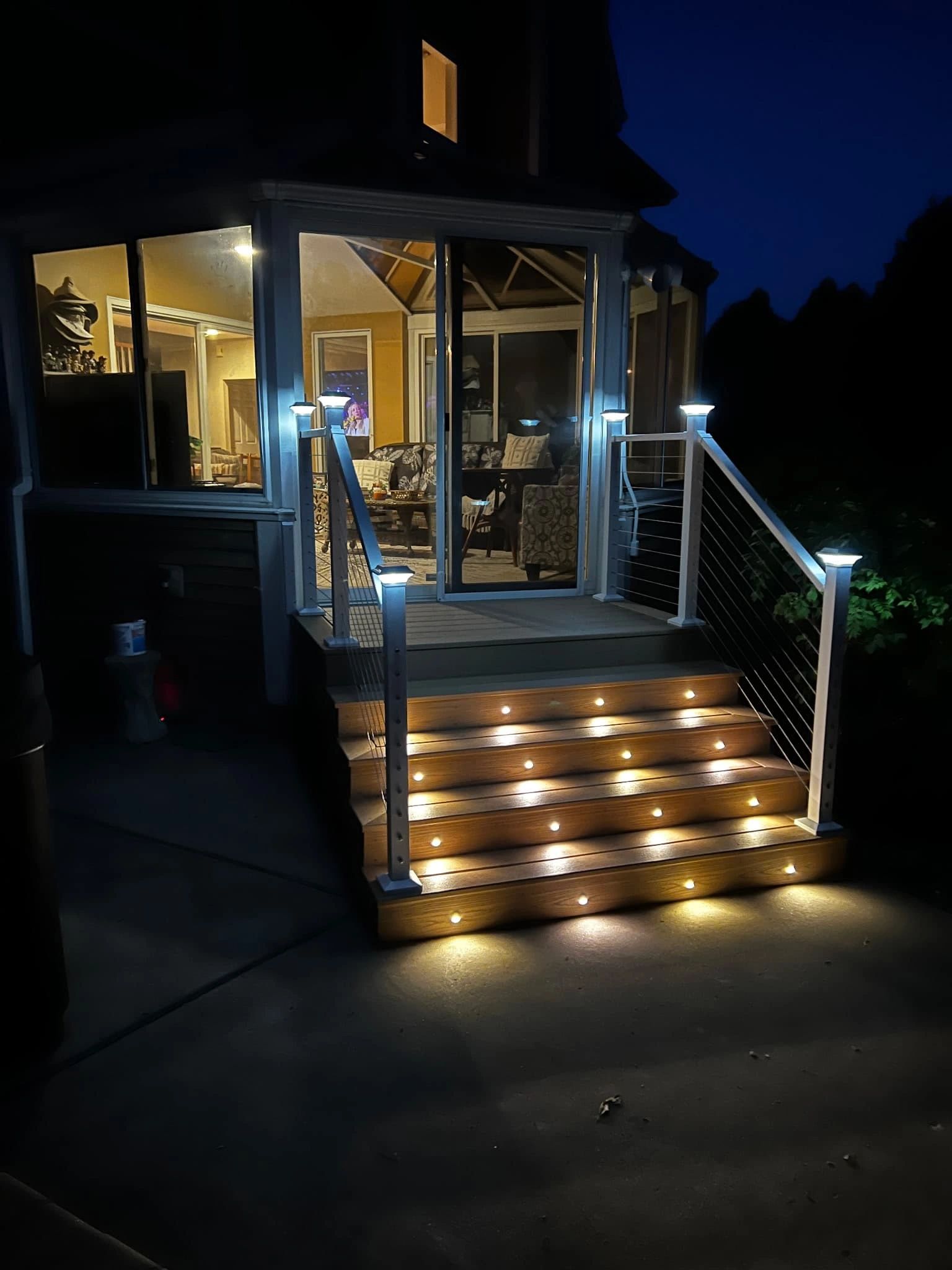 Composite picture frame deck with white cable railing, riser lights, and solar post caps.