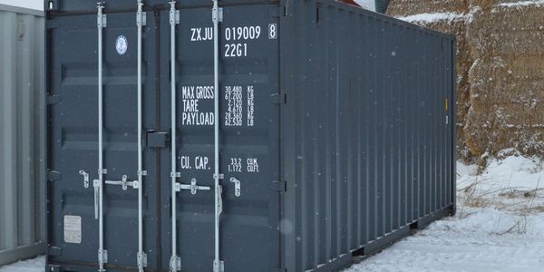 A blue shipping container in a snowy outdoor area.