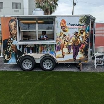 Colorful food truck with musical mural and vendor.
