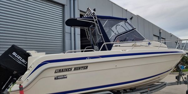 A Shaines Hunter motorboat docked near a warehouse with a Suzuki engine.
