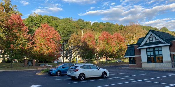 Parking lot with colorful autumn trees and blue sky.