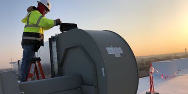 Electrician fixing roof top exhaust vents.