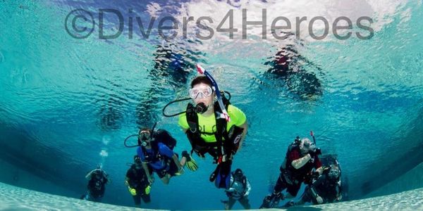Group of scuba divers underwater in a pool.
