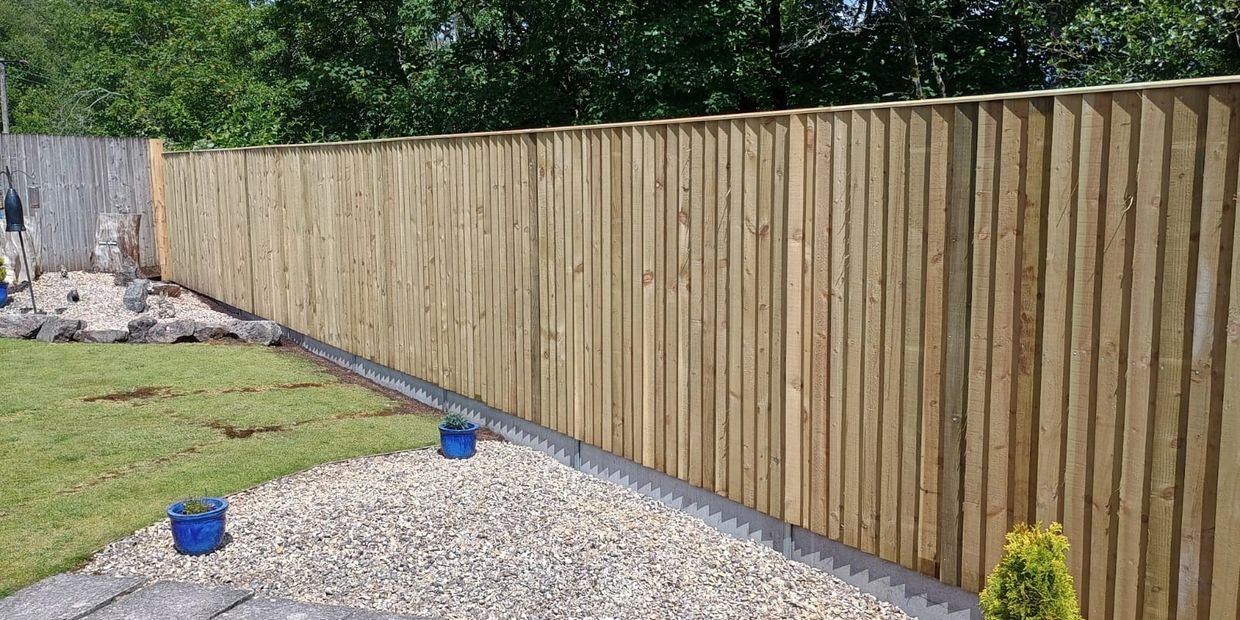A backyard with a wooden fence, gravel area, and potted plants in blue pots.