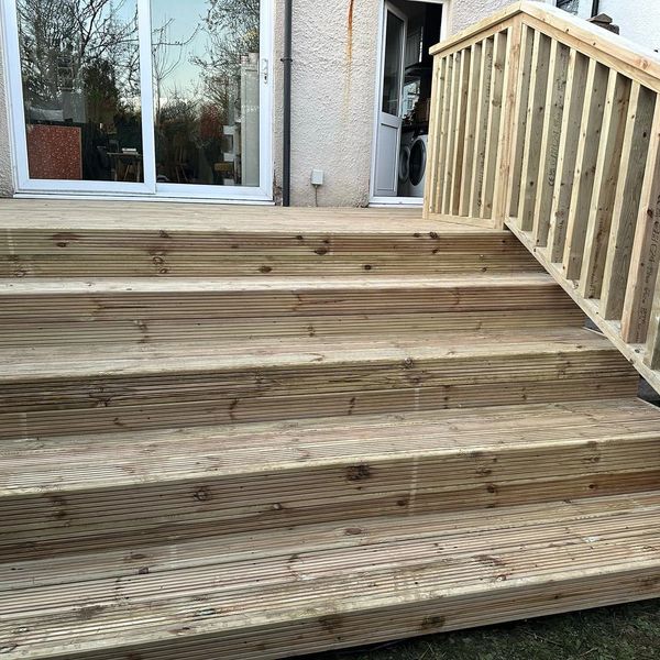 Wooden stairs and deck leading to a house with a glass door.
