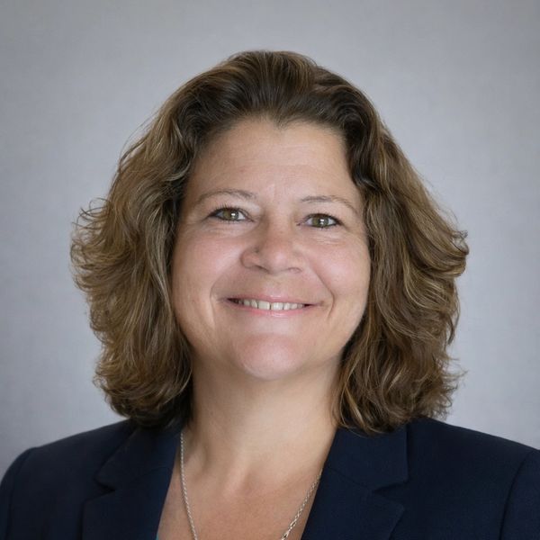 Smiling woman with shoulder-length curly hair in a navy blazer.