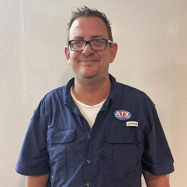 Man in glasses and work shirt smiling.