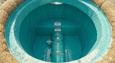 Blue-coated manhole inlet with pipe and labels inside a circular concrete structure.