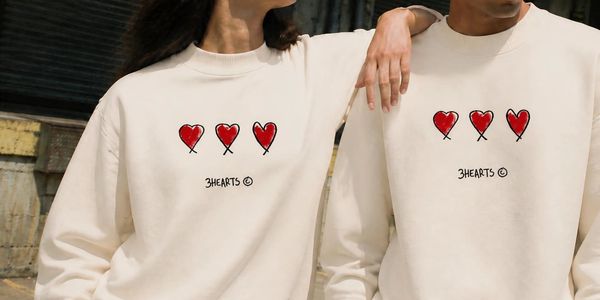 Two people wearing matching 3HEARTS sweatshirts and green pants.