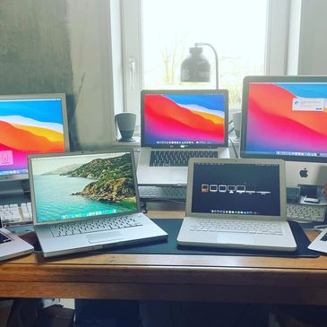 A desk filled with multiple Apple devices including laptops and monitors.
