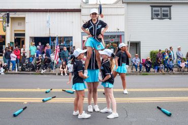 Young girls performing a cheerleading stunt in a street parade.
