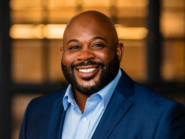 Smiling man in a blue suit and light blue shirt.