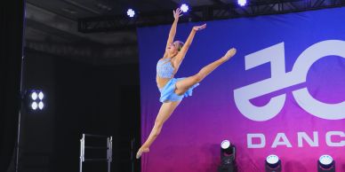 A dancer performing a high jump on stage.