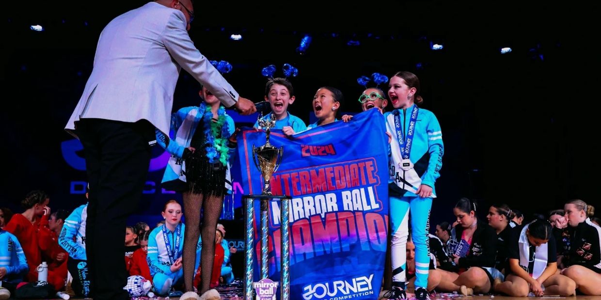 Children celebrating winning the 2024 Intermediate Mirror Ball Championship at a dance competition.