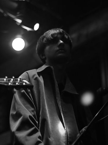 Black and white portrait of a young musician in dim lighting.