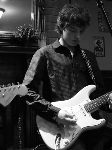 A young man playing an electric guitar in a cozy indoor setting.