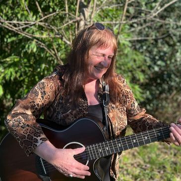 Barbara Anne Oregon Folksinger with her guitar and smiling 