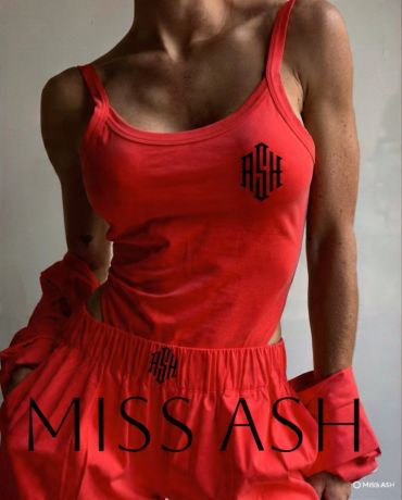 Woman in bright red sporty outfit with 'ASH' logo.