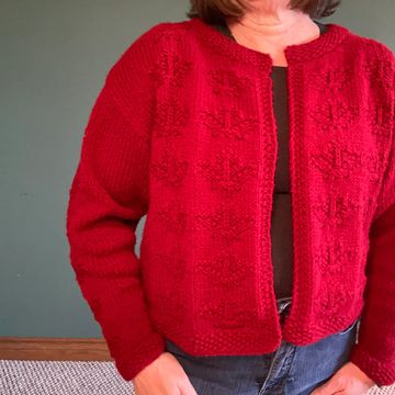 A waist length cardigan with an all over maple leaves design