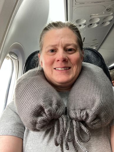 A person on a plane with a stuffable neck pillow