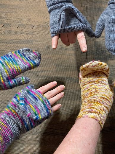 Three pairs of hands wearing flip top mittens. 