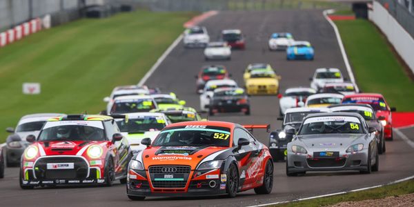 Race cars competing on a professional track during a motorsport event.