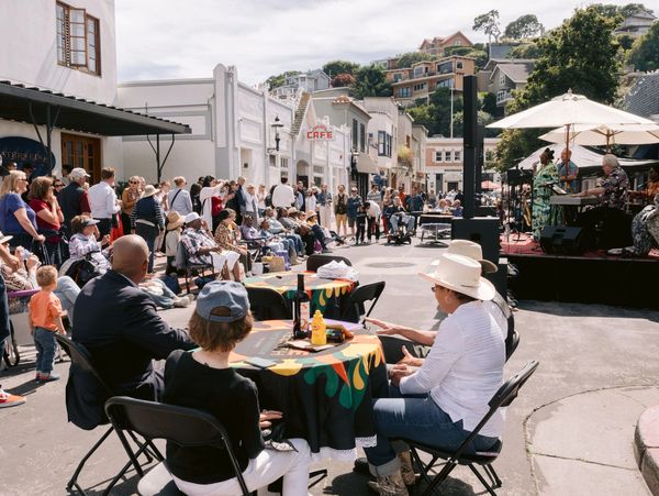 Outdoor street concert with seated audience and performers.