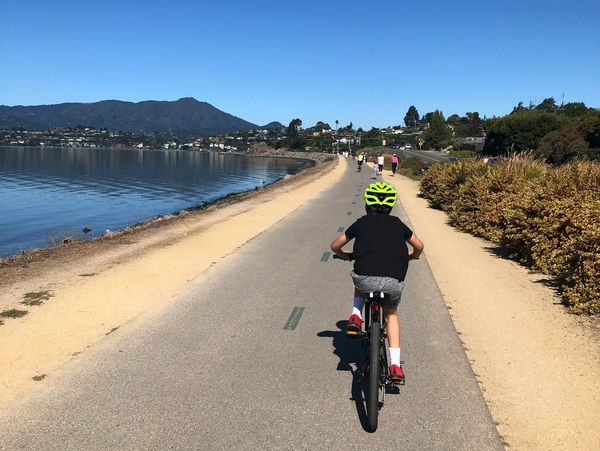 Child biking on a path by the water.