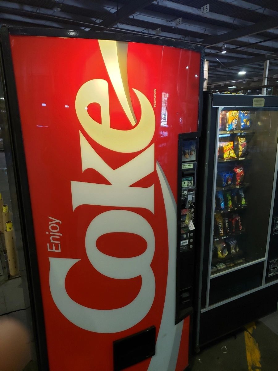 A Coca-Cola vending machine next to a snack vending machine.