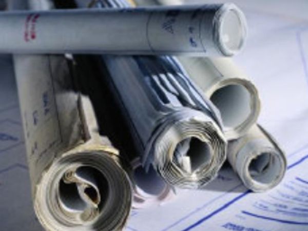 A set of rolled architectural blueprints and plans stacked together.