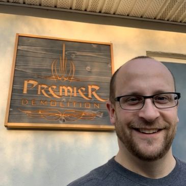 Man smiling in front of Premier Demolition sign.