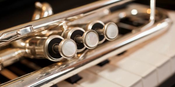 Close-up image of a trumpet on a piano keyboard.
