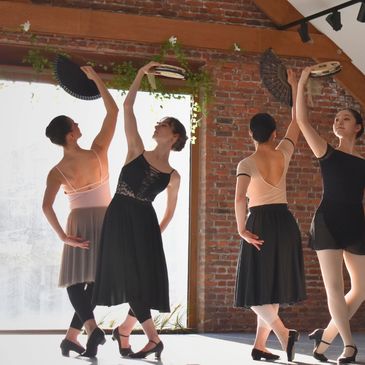 A group of dancers practicing with fans in a loft studio.