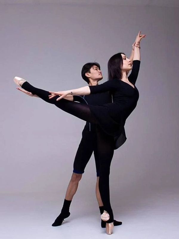Two ballet dancers performing a graceful pose together in a studio. Partnering. Pas De Deux