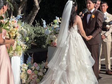 Couple exchanging vows at outdoor wedding ceremony decorated with pastel silk flower rentals at The Harper by Wedgewood Costa Mesa in Orange County CA.