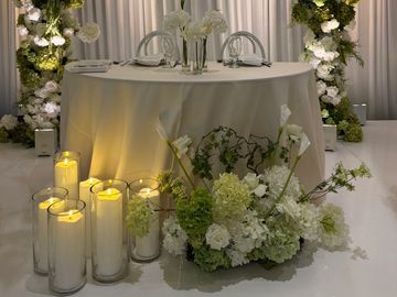 Elegant silk floral sweetheart table decorations with candles and white drapes at The Venue by 3P wedding venue in Orange County CA 