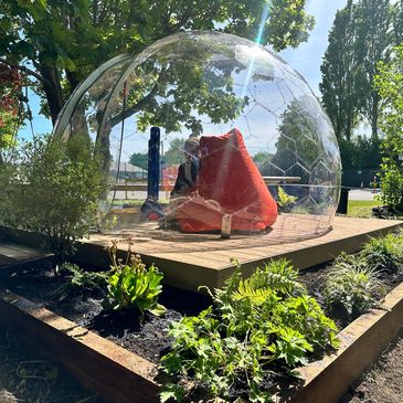 Geodesic dome with a red bean bag in a school garden setting.