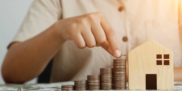 Une personne qui place sa monnaie devant une maison miniature, assurance emprunteur