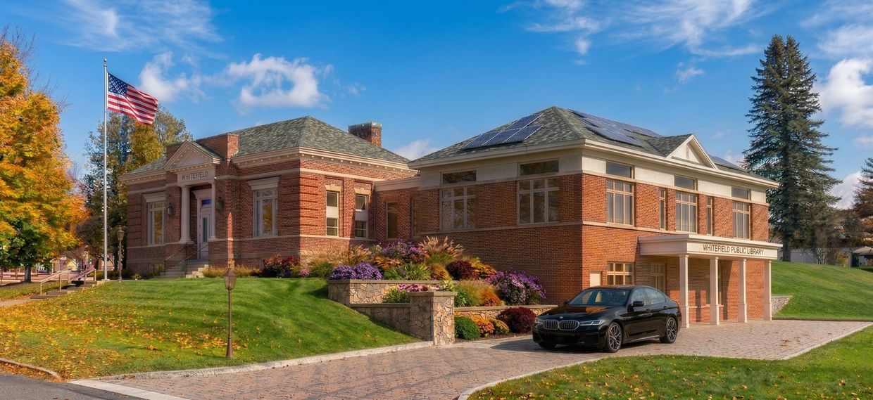 Whitefield Public Library with a parked black car and vibrant autumn foliage.