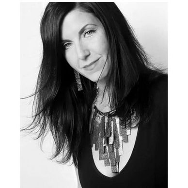 Black and white portrait of a woman with long hair and statement necklace.