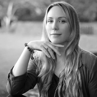 Black and white portrait of a woman with long hair, resting her chin on her hand.