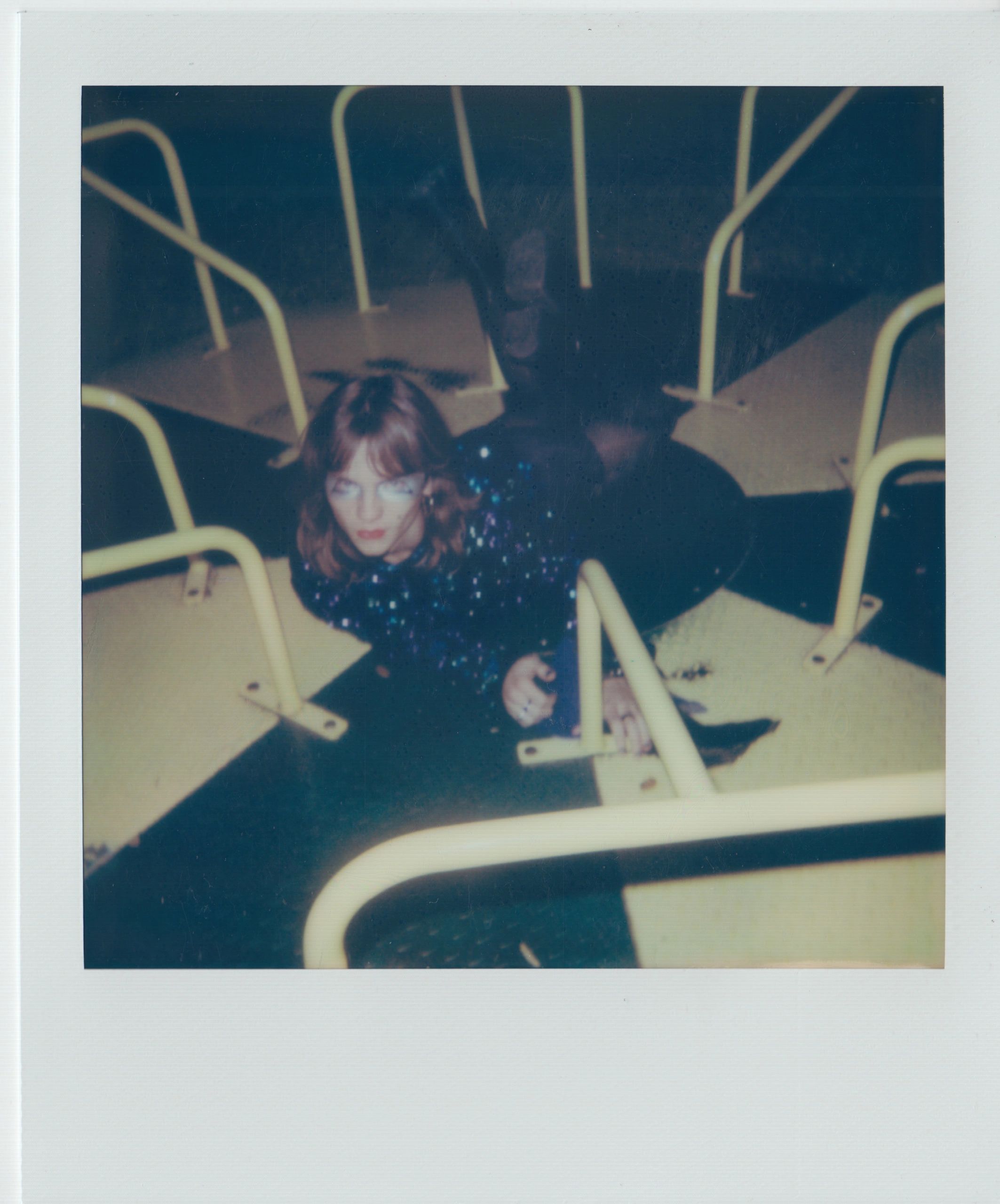 Person lying on their stomach inside a yellow metal playground structure at night.