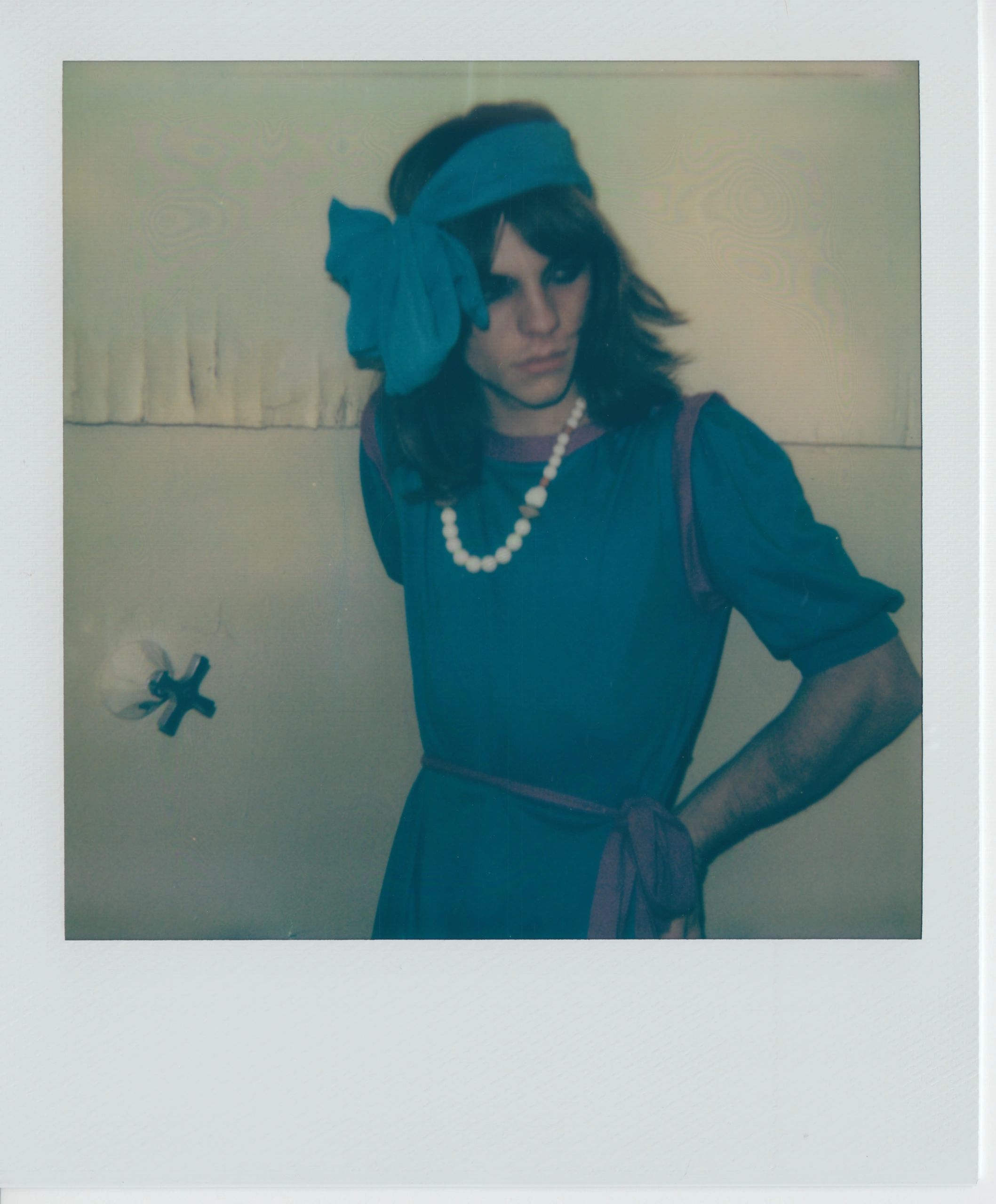 Person in blue dress with headband and pearl necklace.