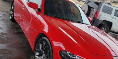 Bright red sports car parked near a white SUV.