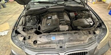 BMW car engine with open hood in a workshop.